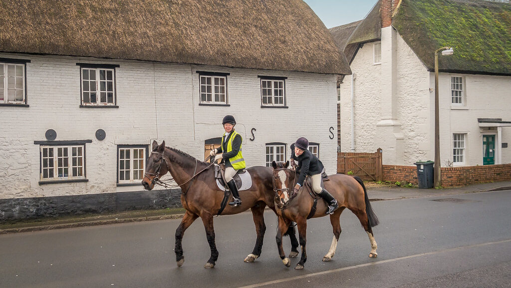 Two horse riders pass through the building