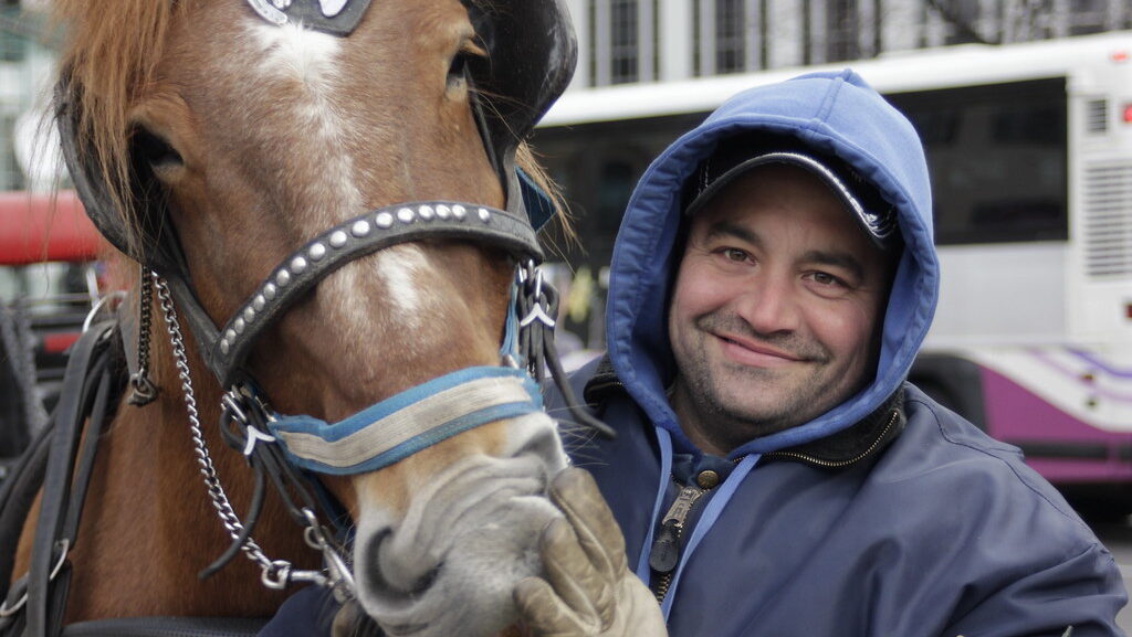 A man standing wuth brown horse