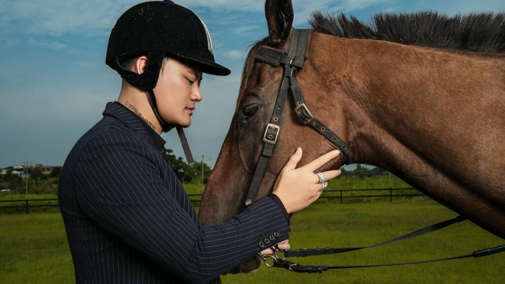 Man bonding with horse in outdoor setting wearing equestrian gear, showcasing human-animal connection.