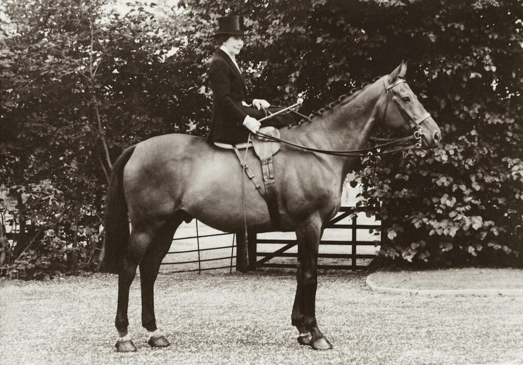 Old photo of a woman in traditional riding attire on a horse