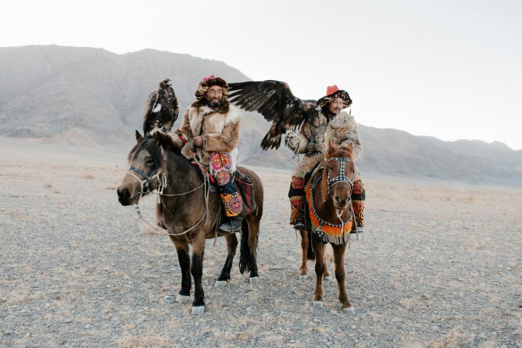 Mongolian eagle hunters on horseback in traditional attire, showcasing vibrant culture.