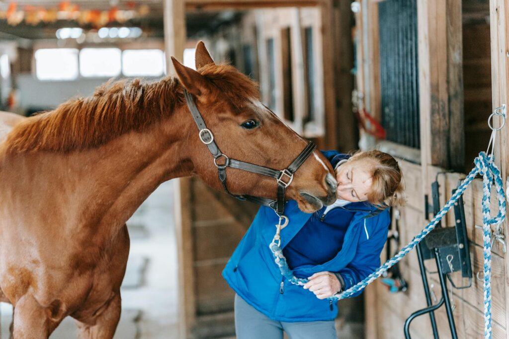 Woman affectionately interacting with horse in a stable