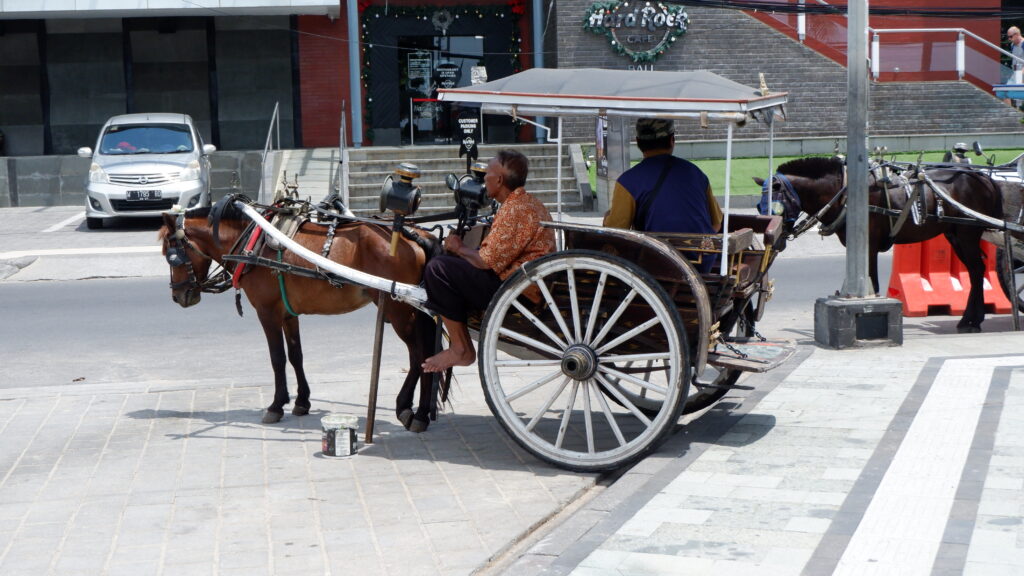"Andong" (horse-drawn carriage) on the road along Kuta Beach