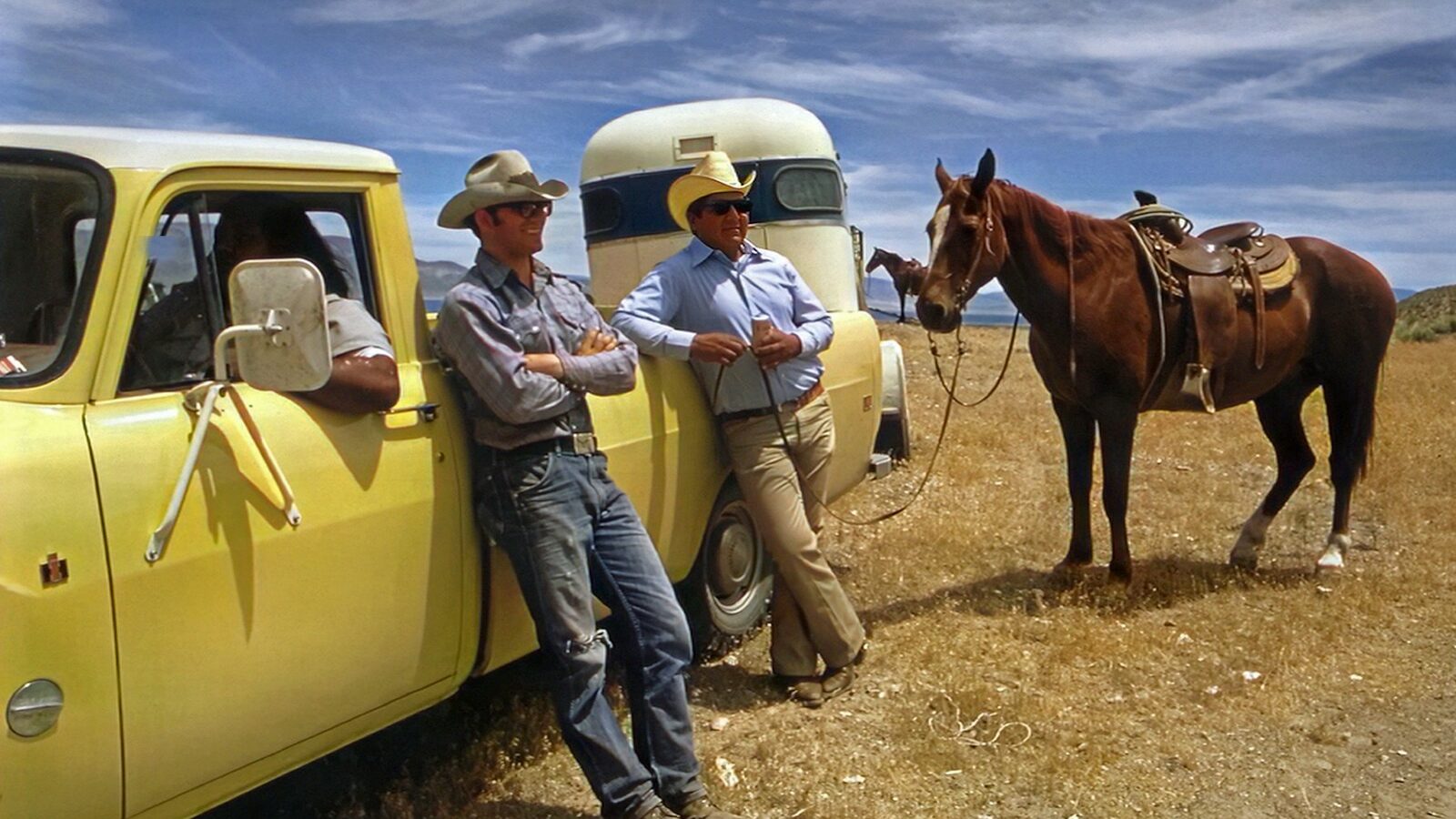 a couple of men standing next to a yellow truck
