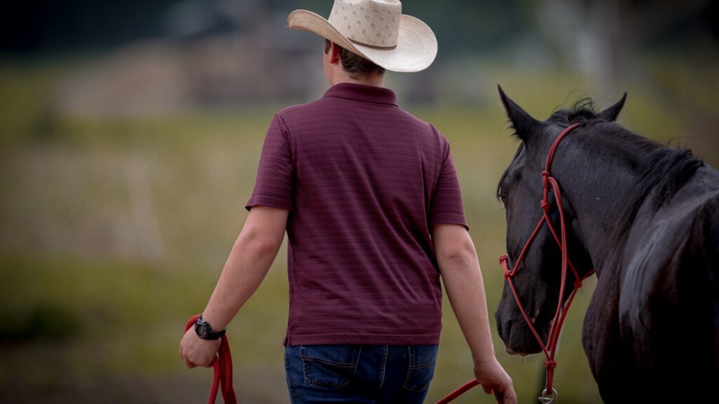 a man in a cowboy hat walking a horse