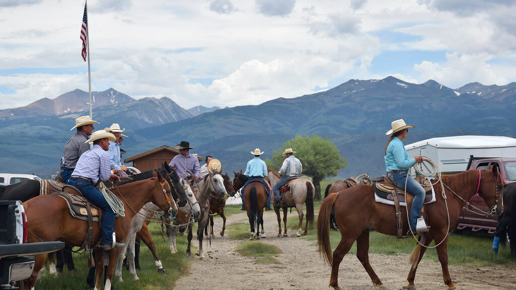 Group of people on horseback in a mountainous rural setting.
