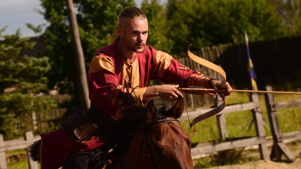 man holding brown wooden stick on the back of horse