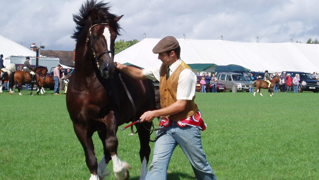 A man in a brown jacket with a horse