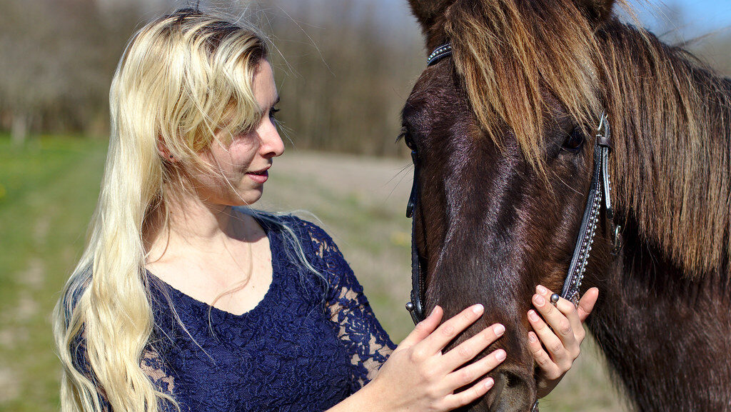 A woman in blue dress talking to a horse