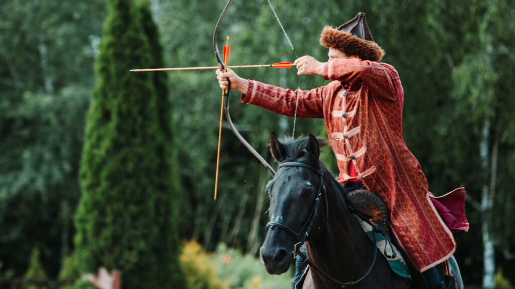 person riding on black horse holding brown compound bow
