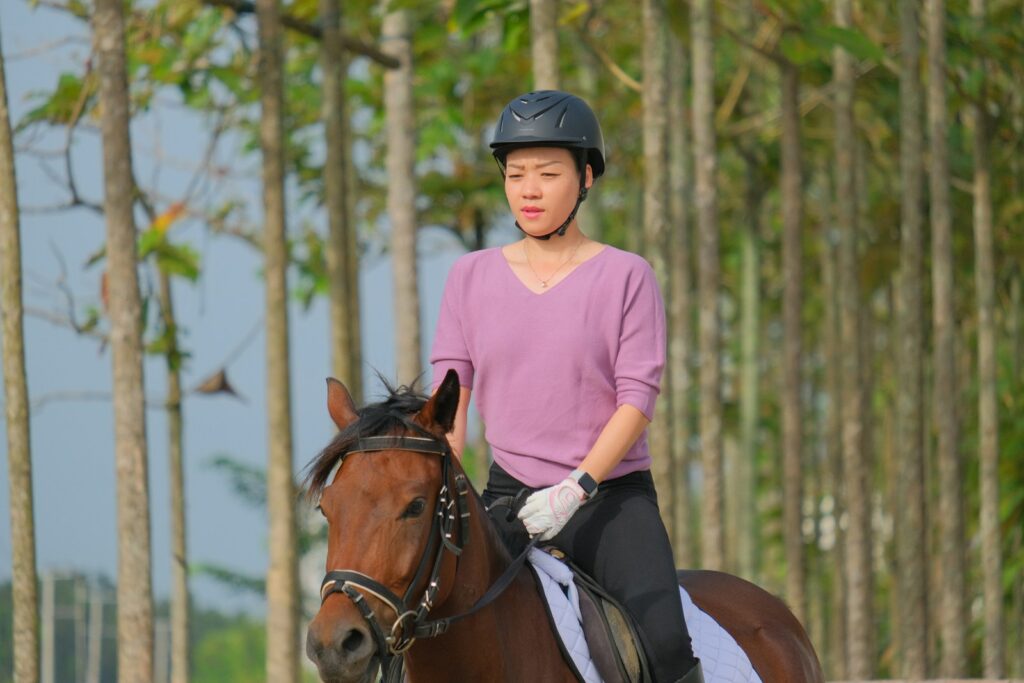 Woman in pink t-shirt riding on brown horse