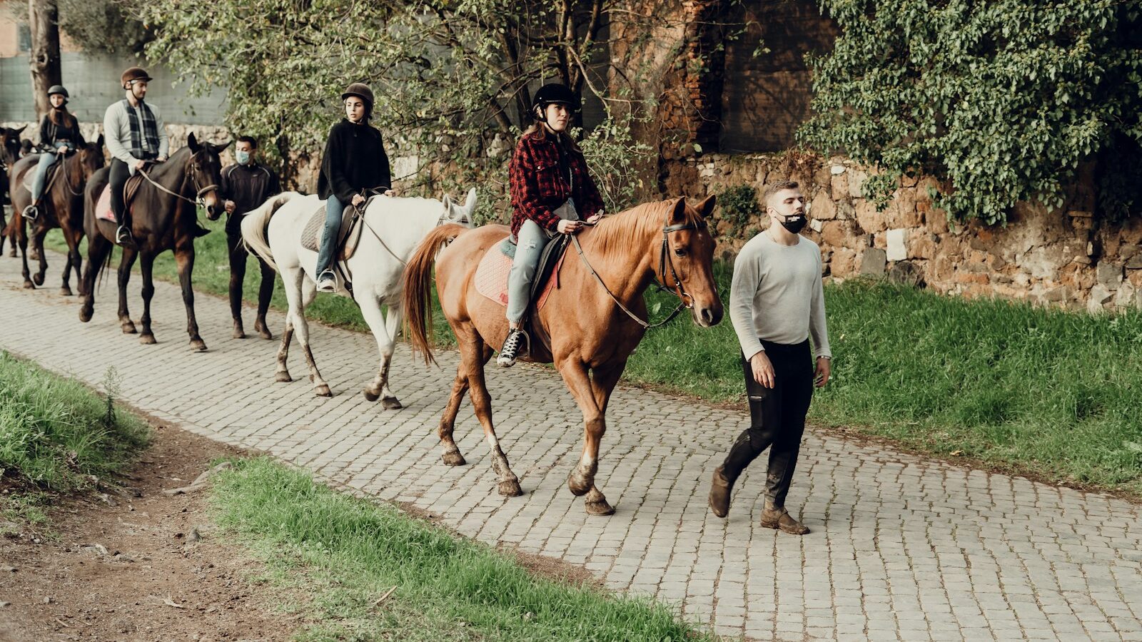man in white long sleeve shirt and black pants walking beside brown horse during daytime