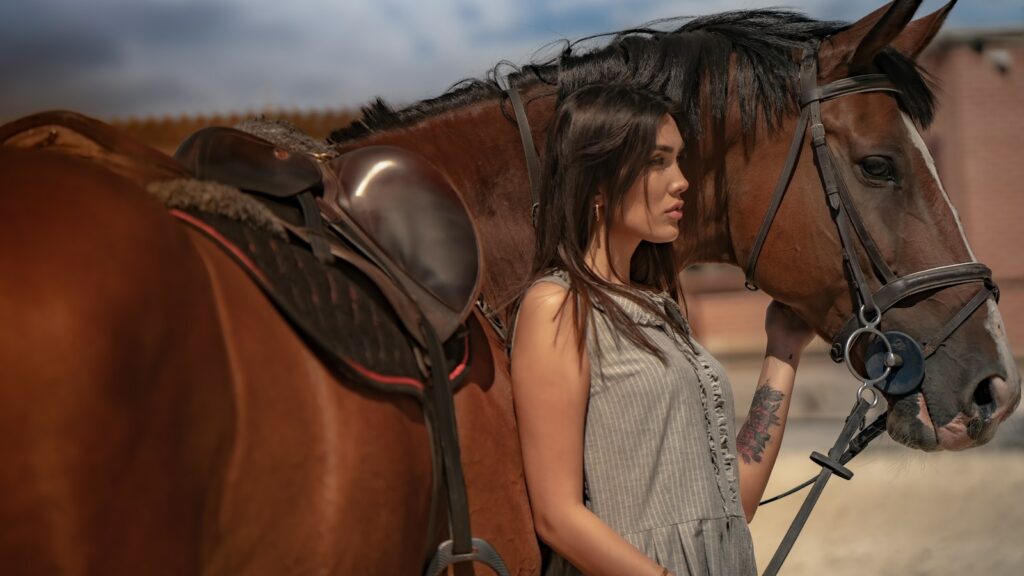 a woman standing next to a brown horse