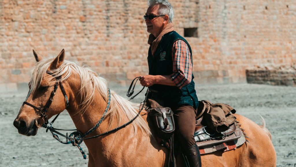 A man is riding a brown horse