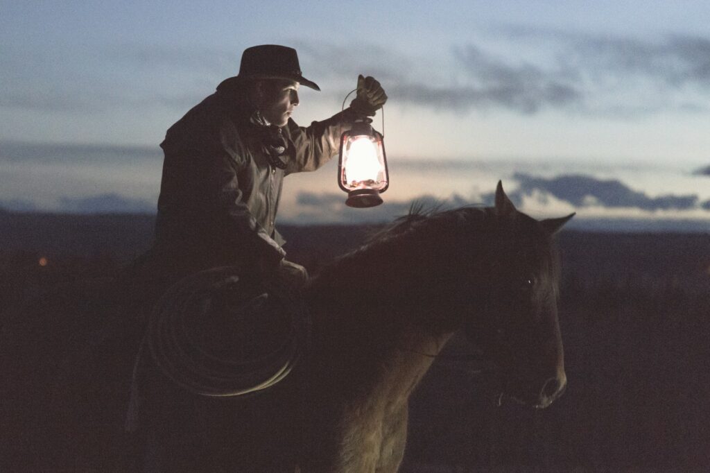 Cowboy riding horse holding lantern