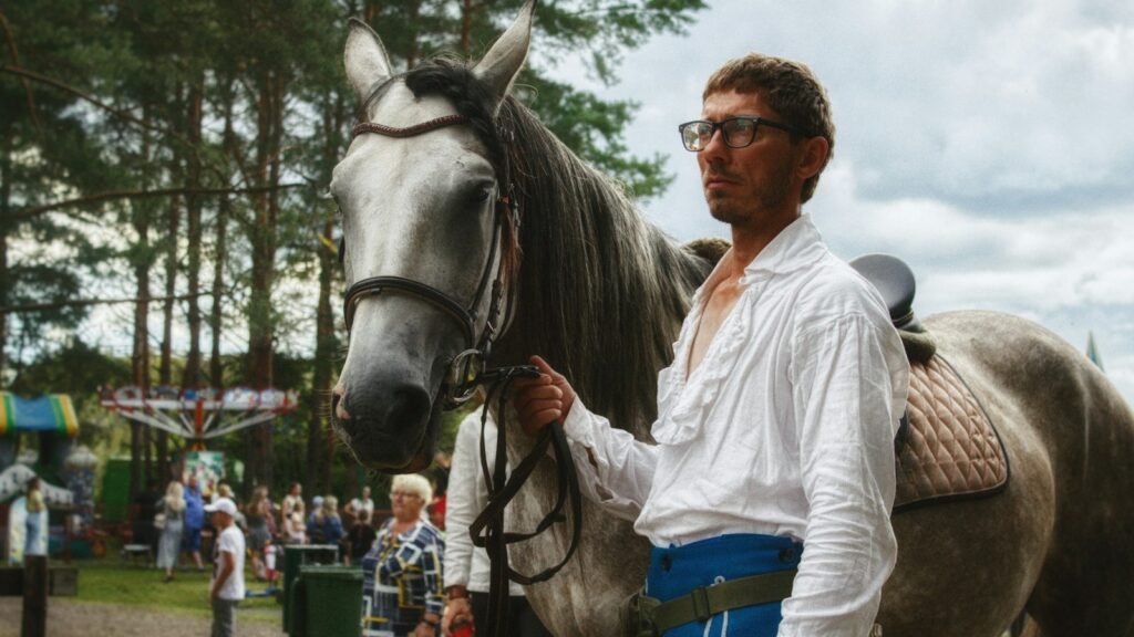 a man standing next to a brown horse