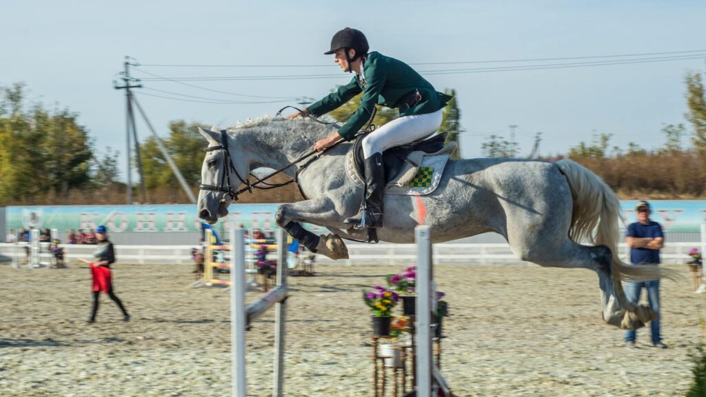 A thrilling moment of a rider and horse mid-jump at a showjumping competition.