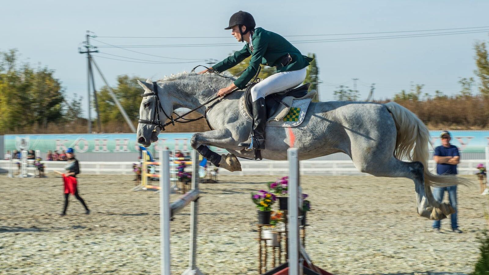A thrilling moment of a rider and horse mid-jump at a showjumping competition.