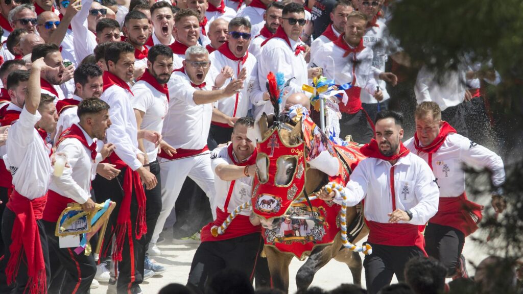 Colorful traditional festival with ornate horse and participants running in Caravaca de la Cruz.