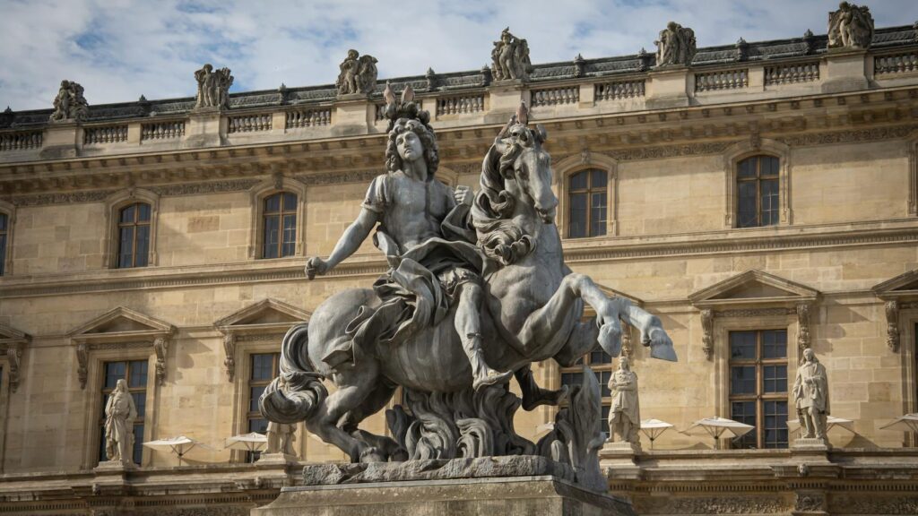Equestrian statue of Louis XIV in front of the Louvre Museum in Paris, displaying classical French sculpture.