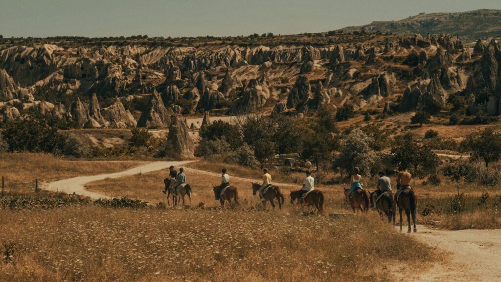 Group horseback riding in captivating Cappadocia rock formations under summer sun.