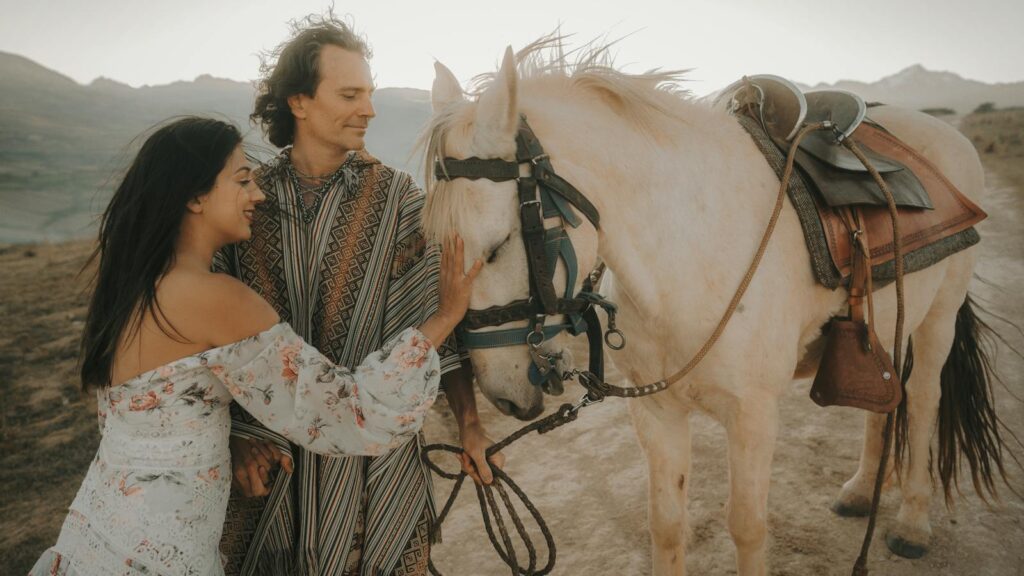 A couple enjoying a serene moment with a horse in a beautiful outdoor setting.