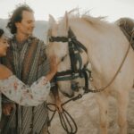 A couple enjoying a serene moment with a horse in a beautiful outdoor setting.