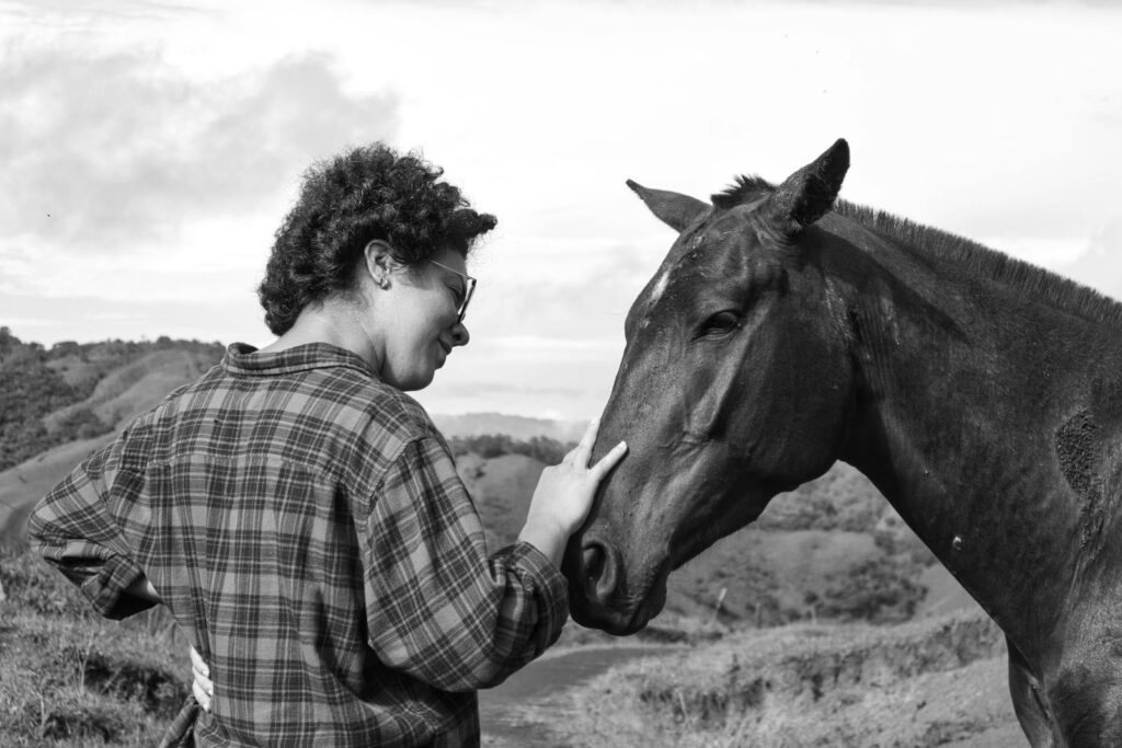 A woman gently pets a horse in the scenic countryside of Costa Rica.