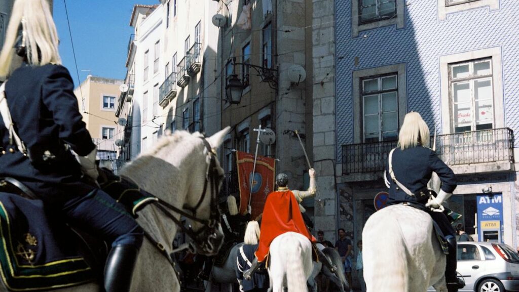 Mounted soldiers parading through Lisbon's historic streets, showcasing vibrant uniforms.