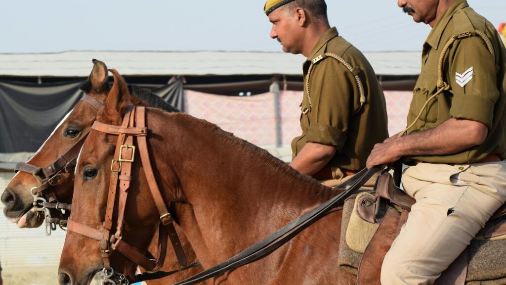 Two mounted police officers on brown horses in India during the day.