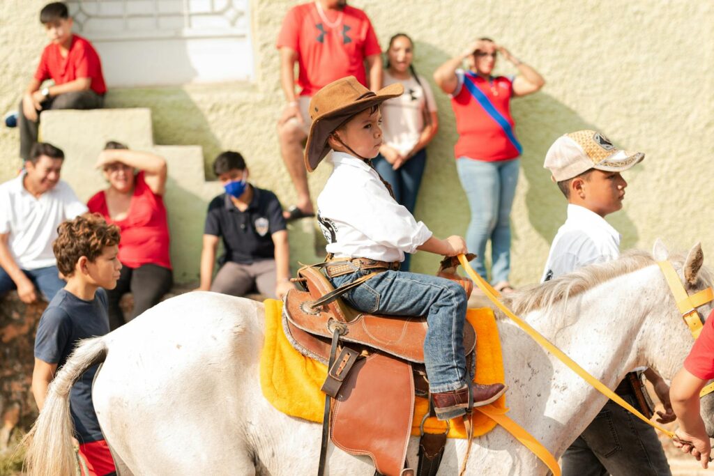 Young boy in cowboy hat on horse in an event