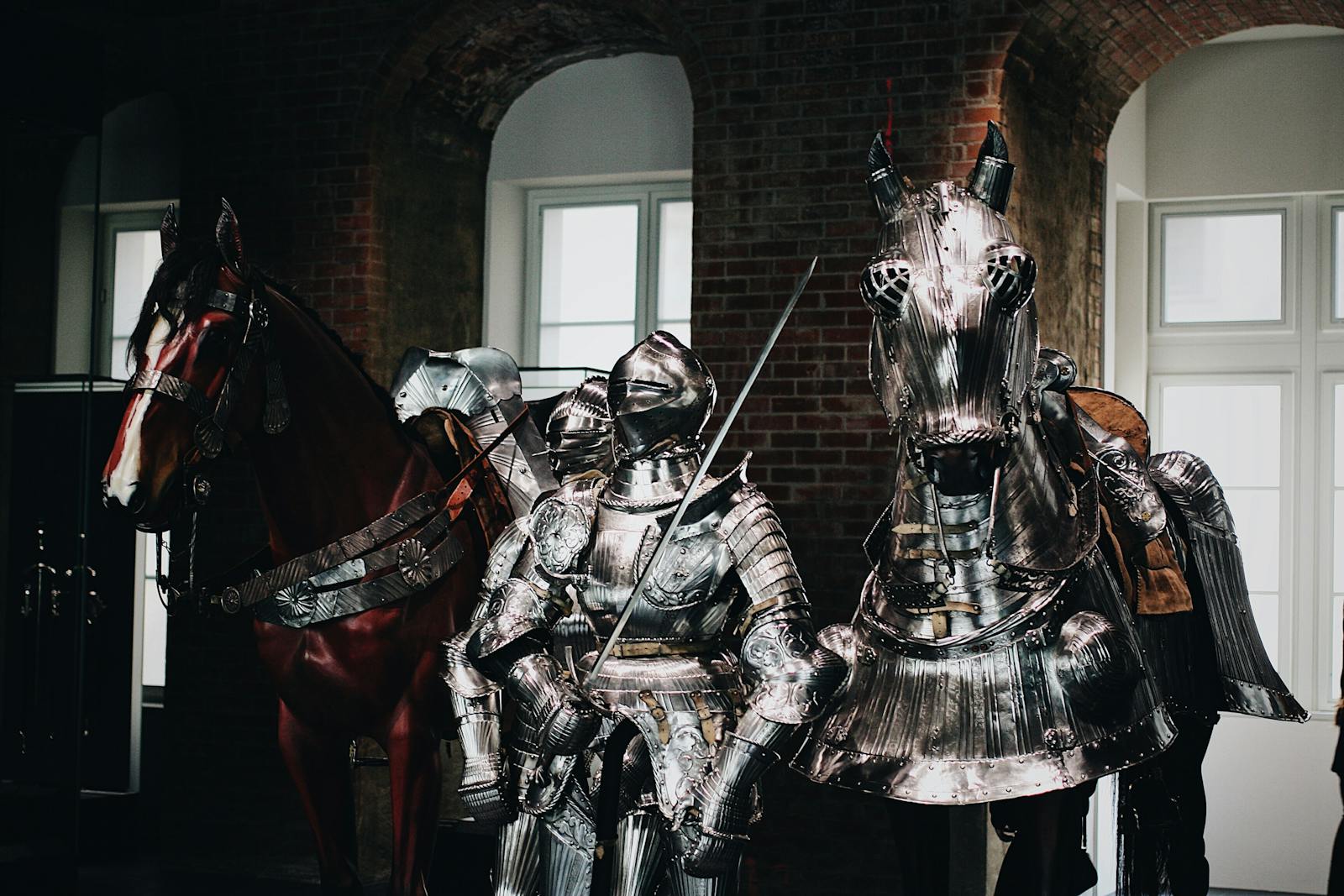 Medieval knight in full armor with a swordsman and armored horse