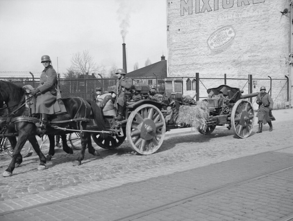 Troops of the German army (Wehrmacht) with draft horses move artillery and equipment, including a 10.5 cm leFH 18 howitz, through the Oslo gate Street in Oslo, Norway in April 1940