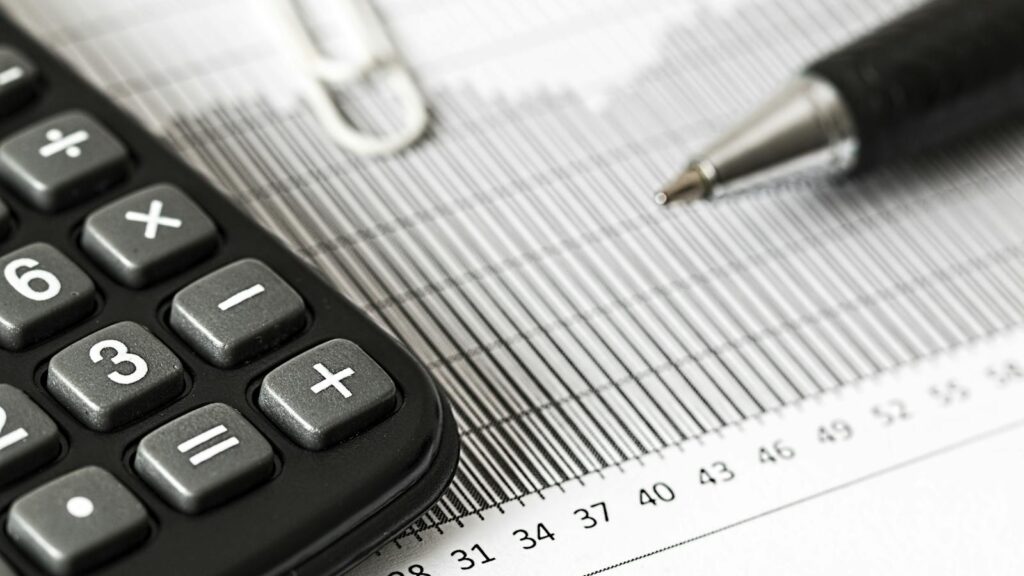 Close-up of a calculator and pen on a bar graph, representing finance and accounting.