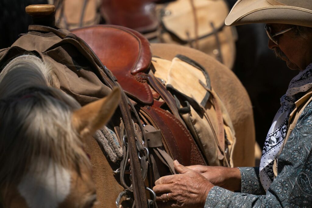 Cowboy adjusting a saddle on a horse