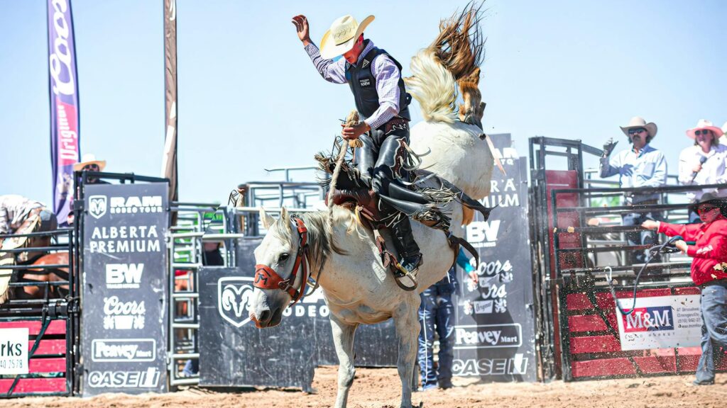 Dynamic image of a cowboy expertly riding a bucking bronco during a rodeo competition.