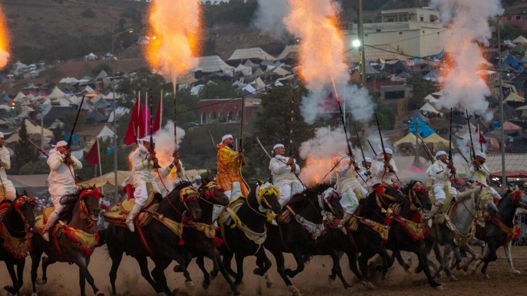 A group of Moroccan horsemen perform a Tbourida display with smoke and fire in Sidi Moussa El Mejdoub.