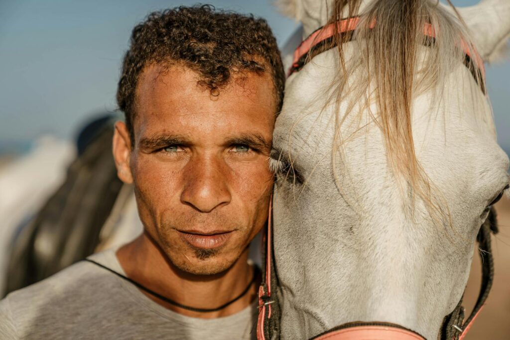 A close-up portrait of a man with a white horse in Dahab, Egypt, showcasing their connection.