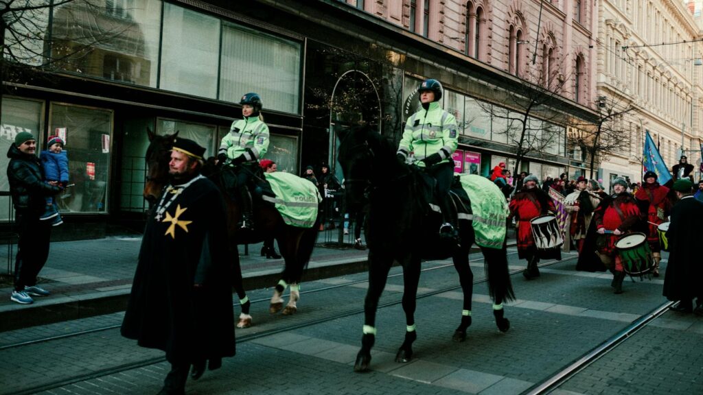 Colorful city parade featuring mounted police and festive participants on a busy street.