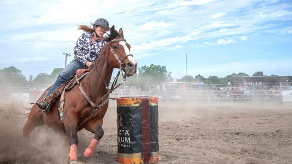 Dynamic barrel racing scene capturing horse and rider in an outdoor rodeo setting.