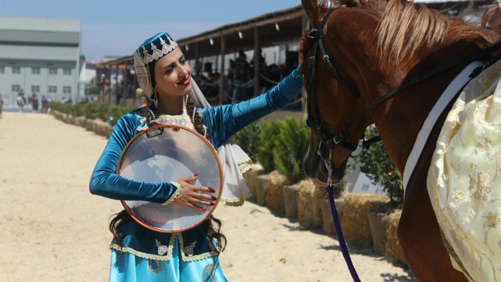 Woman in traditional attire with a horse at a Turkish festival in Istanbul, Türkiye.