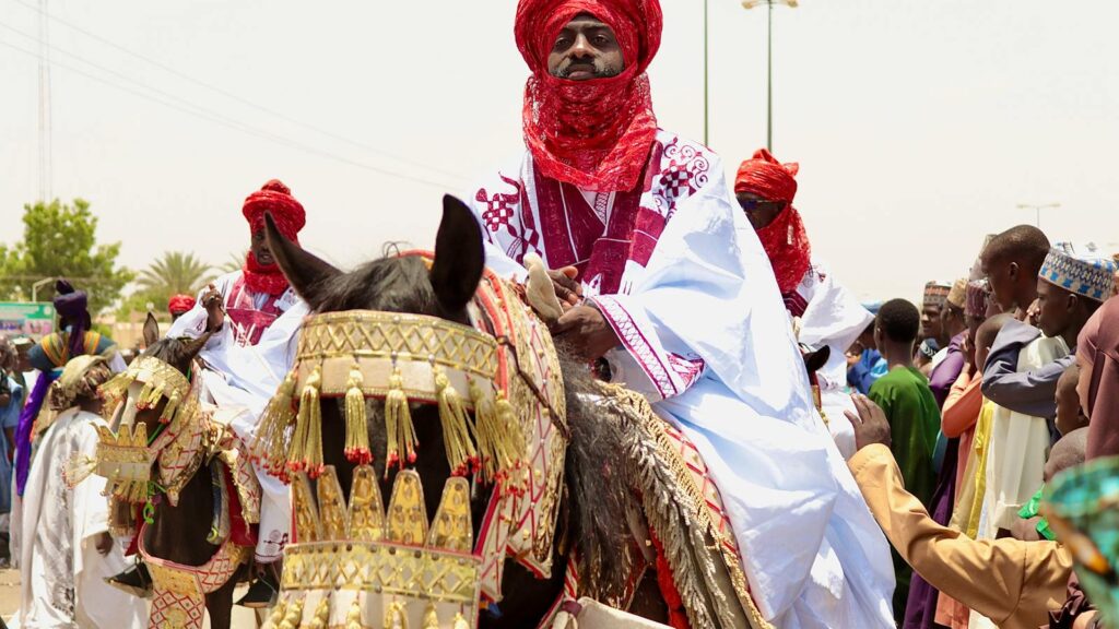 Colorful Durbar festival in Bauchi, Nigeria with riders in traditional attire on decorated horses.
