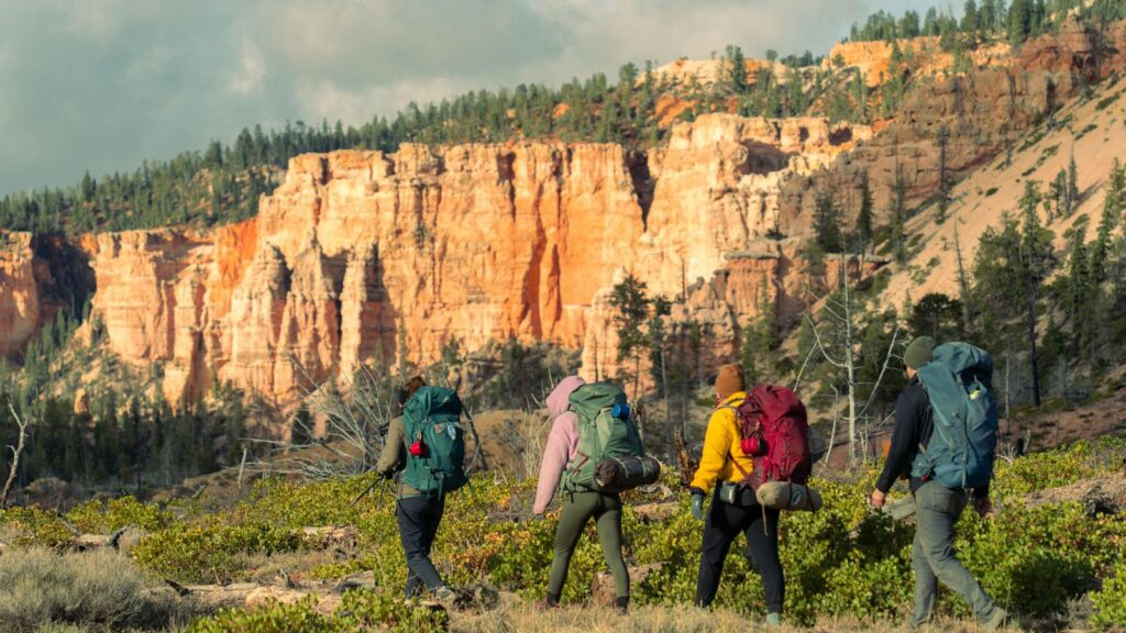 Group of hikers trekking through Bryce Canyon National Park, Utah, with vibrant red rock formations.