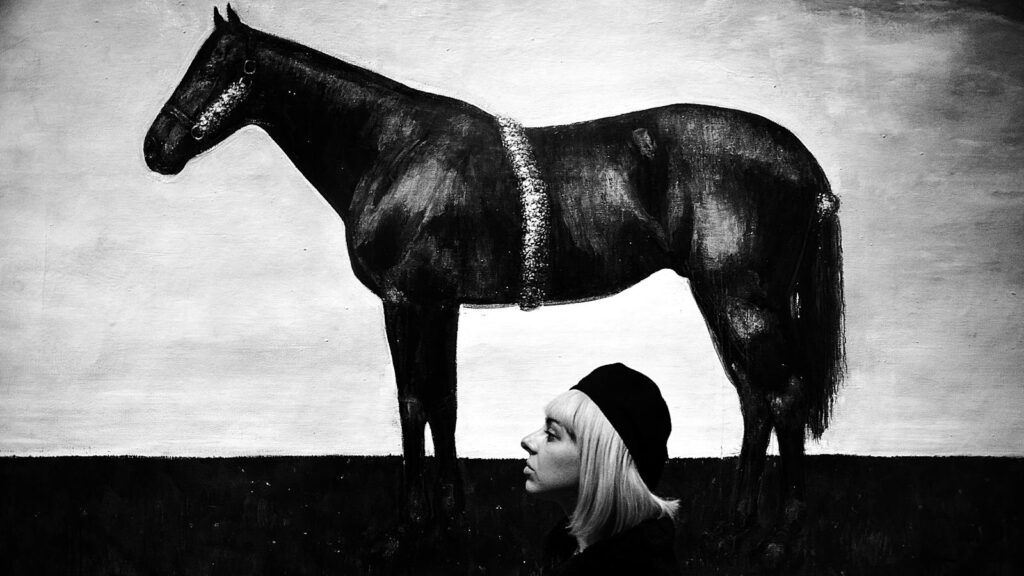 Artistic black and white portrait of a woman beside a horse mural in Zagreb.