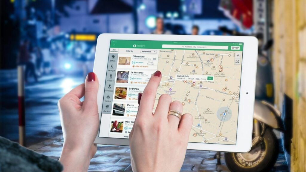 Hands using a digital map on a tablet in an urban setting at night, illustrating navigation and technology.