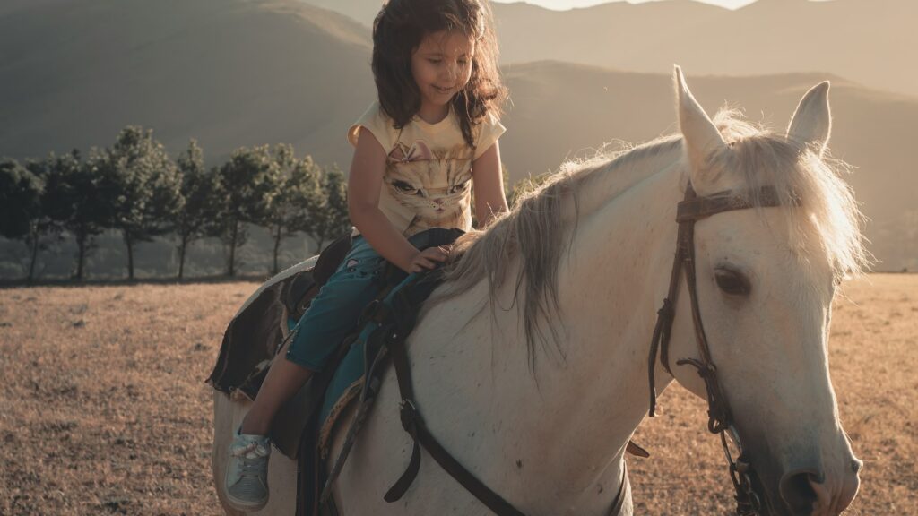 woman in white shirt riding white horse during daytime