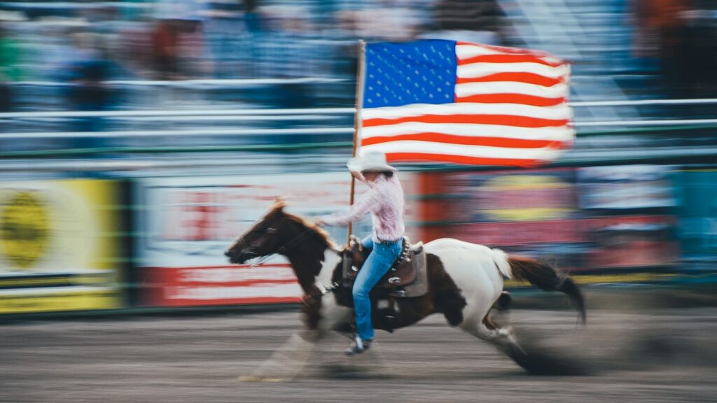 time lapse photo of man carrying U.S. flag while riding brown horse