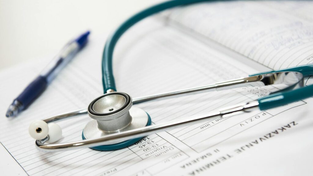 A stethoscope and pen resting on a medical report in a healthcare setting.
