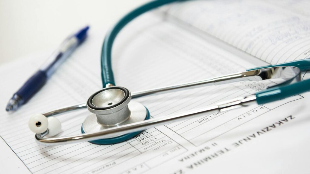 A stethoscope and pen resting on a medical report in a healthcare setting.
