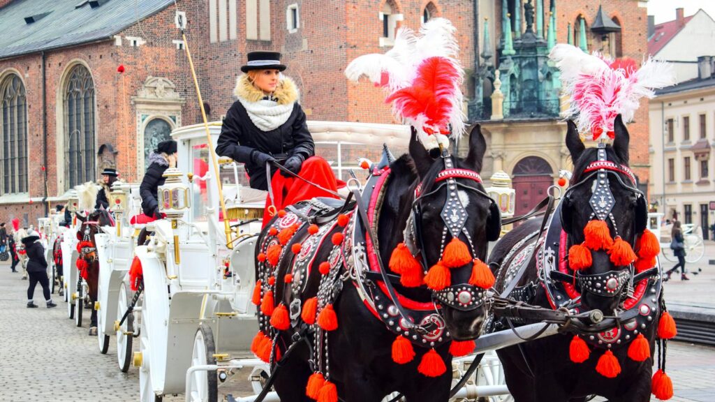Elegant horse-drawn carriages adorned with red tassels in Krakow city square.